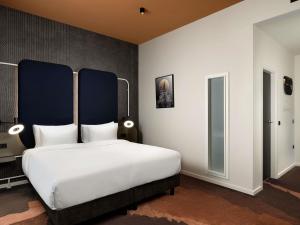 a bedroom with a large white bed with a blue headboard at You Hotel Budapest - Handwritten Collection in Budapest