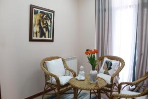 ein Zimmer mit zwei Stühlen, einem Tisch und einer Vase mit Blumen in der Unterkunft Hotel Sfinks Elbasan Albania in Elbasan