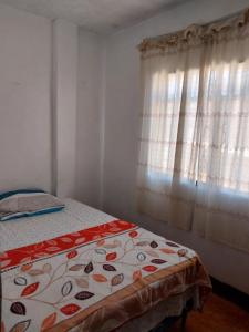 a bedroom with a bed and a window with curtains at Casa Ibañez in Talara