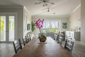 a dining room with a table with a vase of flowers at Springtide House -Dock & Home w Pool in Stock Island