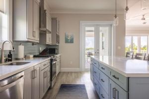 a large kitchen with white cabinets and a large window at Springtide House -Dock & Home w Pool in Stock Island