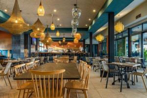 a restaurant with wooden tables and chairs and chandeliers at The Blyde Luxury Apartments in Pretoria