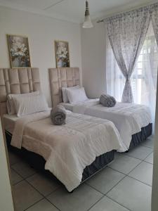 two beds sitting next to each other in a bedroom at The Blyde Luxury Apartments in Pretoria +20 photos