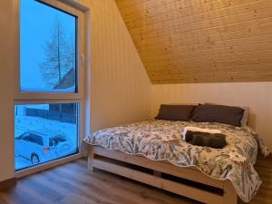 a bedroom with a bed and a large window at OAK House domek z balią w Serskim Lesie in Las Dalny