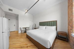 a bedroom with a white bed and a table at Tri Century Mill Suites in Carleton Place
