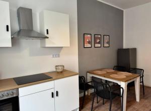 a kitchen with white cabinets and a table with chairs at Appartement "Peter" in Köthen mit 3 Schlafzimmern in Köthen