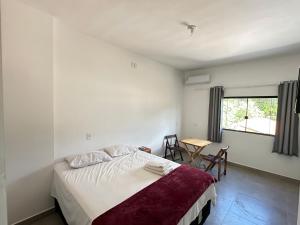 a bedroom with a bed and a table and a window at Pousada caminho das águas in Pirenópolis +51 photos