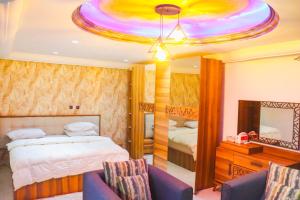 a bedroom with a bed and two chairs and a mirror at Brazza Hôtel in Brazzaville