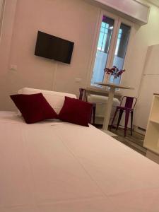 a white bed with red pillows in a bedroom at Mini white apartment in Scandicci