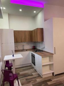 a kitchen with a sink and a table with purple lights at Mini white apartment in Scandicci