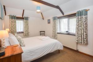 a bedroom with a white bed and two windows at 2 Bed in Padstow oc-w3658 in Saint Merryn