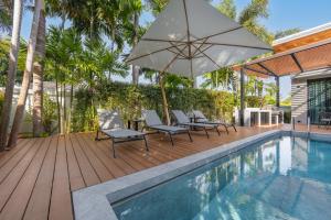 a patio with chairs and an umbrella next to a swimming pool at VILLA PULAU 3 bedroom Baan Bua Estate in Nai Harn Beach