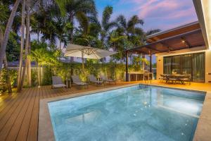 an indoor swimming pool with a patio and a house at VILLA PULAU 3 bedroom Baan Bua Estate in Nai Harn Beach