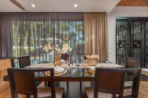 a dining room with a table and chairs and a window at VILLA PULAU 3 bedroom Baan Bua Estate in Nai Harn Beach
