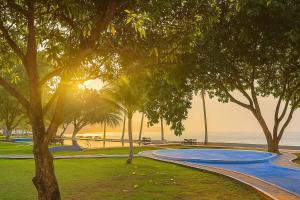 a park with trees and a path next to the ocean at La Plage Beach Club in Tjikakaka