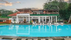 a villa with a swimming pool in front of a house at La Plage Beach Club in Tjikakaka