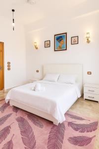 a bedroom with a large white bed and a pink rug at Villa Desert Rose in Luxor