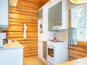 a kitchen with white appliances and wooden walls at Holiday Home Kranni 1 by Interhome in Syöte