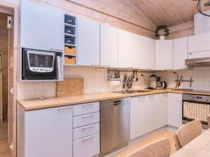 a kitchen with white cabinets and a microwave at Holiday Home Isokuru 3 by Interhome in Pyhätunturi
