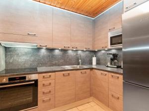 a kitchen with wooden cabinets and a stainless steel refrigerator at Holiday Home Joikupirtti a by Interhome in Pyhätunturi