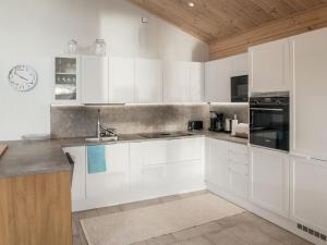 a kitchen with white cabinets and a clock on the wall at Holiday Home Leinola by Interhome in Sotkamo