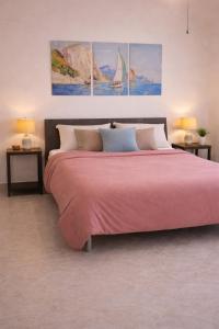 a bedroom with a pink bed with three paintings on the wall at Casa Alfonso in Minori
