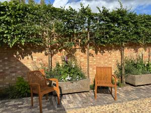 two wooden chairs sitting in front of a brick wall at The Menagerie in Towcester