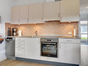 a kitchen with white cabinets and a sink and an oven at Apartment Elevus - 10m from the sea by Interhome in Bogense +7 photos