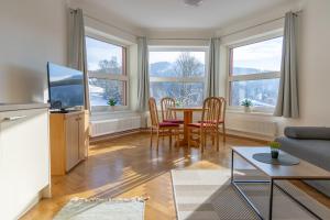 a living room with a table and chairs and windows at Villa Weber Apartments in Albrechtice v Jizerských horách