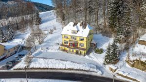 a yellow house in the snow on a mountain at Villa Weber Apartments in Albrechtice v Jizerských horách