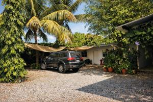 a car parked in front of a house with a palm tree at Habitación Agua - Villa Valle Campo in Nahuizalco