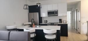 a kitchen with a white counter and some chairs at ChessKings Apartments in Winnipeg
