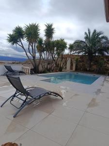 a chair sitting next to a swimming pool with palm trees at Veronica Villa in Partaloa +29 photos