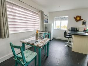 a kitchen with a table and chairs and a refrigerator at Hafod Wen in Pentraeth +6 photos