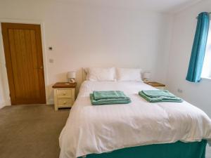 a bedroom with a bed with two towels on it at Hafod Wen in Pentraeth