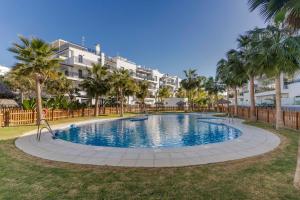 a large swimming pool with palm trees and buildings at RentitSpain - Playa Granada - Apartamentos TRM Aguacate Relax entre Mar, Golf y Montaña in Motril