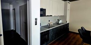 a kitchen with white cabinets and a sink at ZIBO APARTMENTS LESKO Nowoczesne apartamenty z jacuzzi i widokiem na Bieszczady in Lesko +13 photos