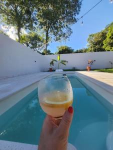 a person holding a glass of beer next to a swimming pool at La Calma San Bernardino in San Bernardino