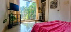 a bedroom with a pink bed and a large window at GS Home on the Bay- Super Sea & Garden view Glass studio apartment in Vagator