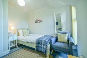 ein kleines Schlafzimmer mit einem Bett und einem blauen Stuhl in der Unterkunft Kylelachin in Dingwall