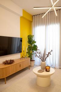 a living room with a flat screen tv and a table at Ophelia's - Luxury Apartment in Volos