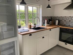 a kitchen with white cabinets and a sink and a window at Annekset - Bjørnø in Faaborg