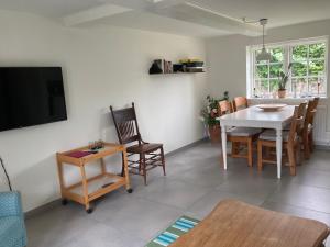 a living room with a table and chairs and a tv at Annekset - Bjørnø in Faaborg