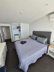 a bedroom with a large bed with blue pillows at 2 Room Luxury Beach Escape 112sq Mt Maunganui in Mount Maunganui