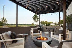 a patio with a fire pit and chairs and tables at LivSmart Studios By Hilton Kokomo in Kokomo