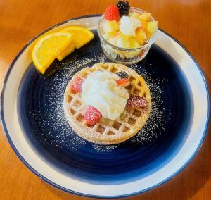 a blue plate with a waffle with whipped cream and fruit at Auberge Foin de mer in Kamouraska +39 photos