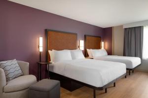 a hotel room with two beds and a chair at LivSmart Studios By Hilton Kokomo in Kokomo +47 photos