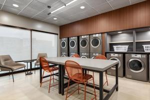 a laundry room with a table and chairs and washing machines at LivSmart Studios By Hilton Kokomo in Kokomo
