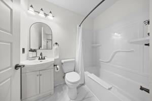 a white bathroom with a toilet and a sink at Tri Century Mill Suites in Carleton Place