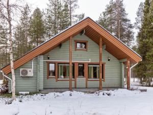 a green house with a brown roof in the snow at Holiday Home Sallassi by Interhome in Salla
